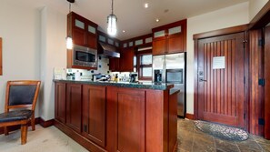 Une cuisine dotée de meubles en bois, d’appareils électroménagers en acier inoxydable et d’un grand îlot central.