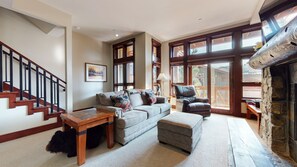 A living room with a fireplace, a sofa, a coffee table, and a staircase.