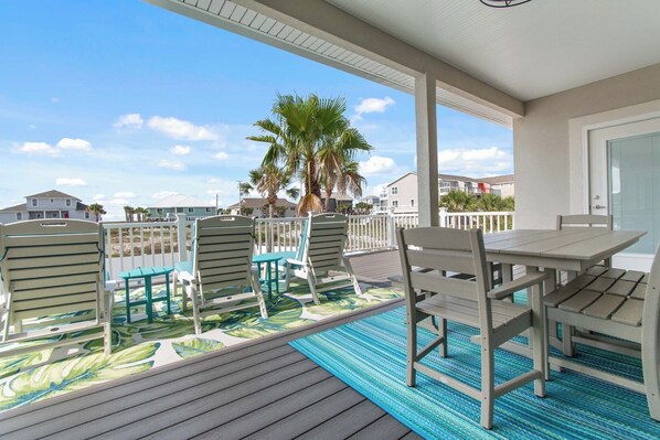 A covered outdoor area with a pool, chairs, and a table.