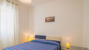Een slaapkamer met een bed, nachtkastjes, een lamp en een schilderij aan de muur.
