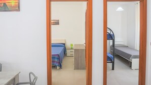 Een kamer met een bureau, twee bedden, een stoel en een schilderij.