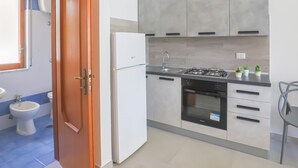 Een moderne keuken met witte kasten, een koelkast, een fornuis en een spoelbak.