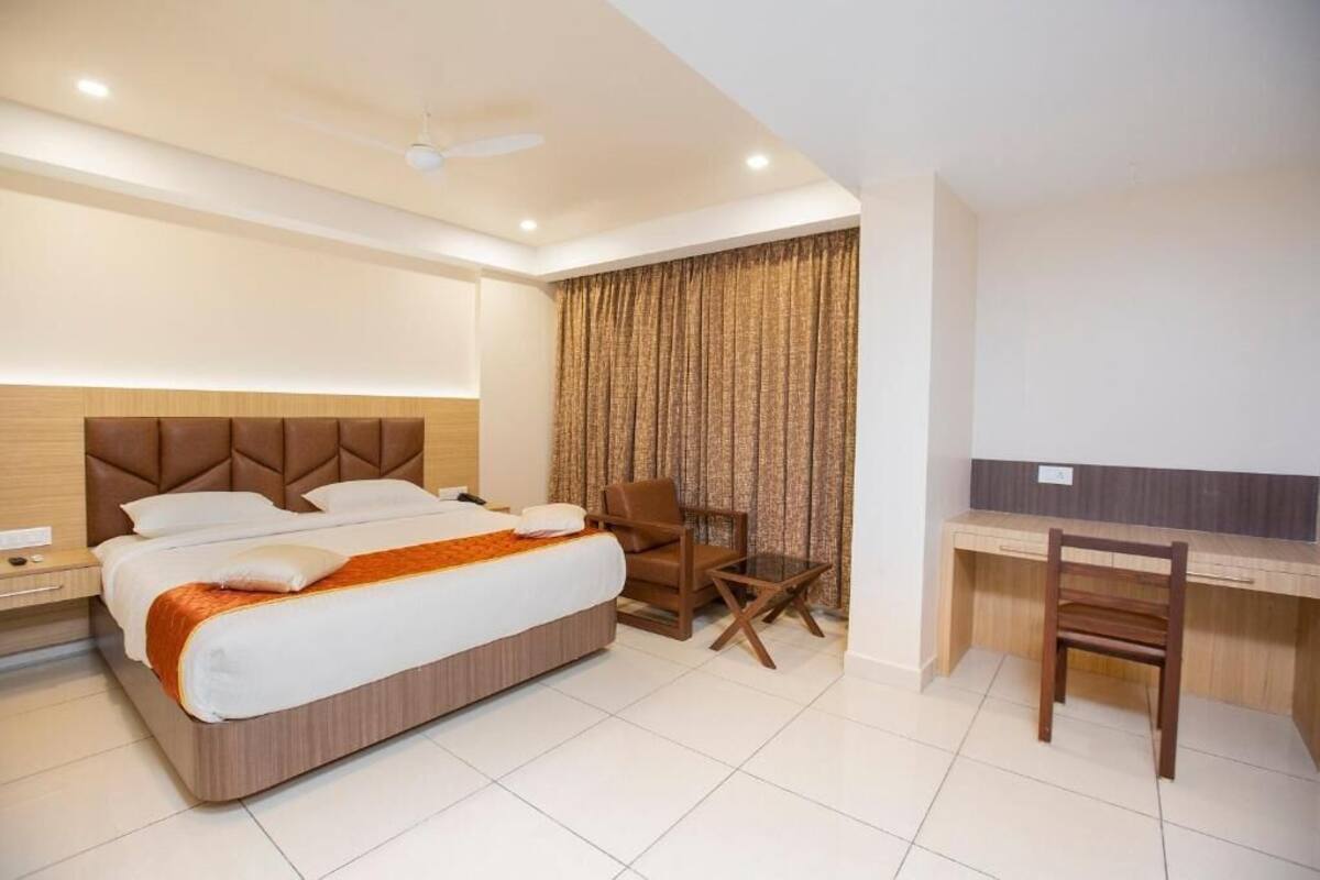 A hotel room with a bed, a desk, a chair, and a curtain.