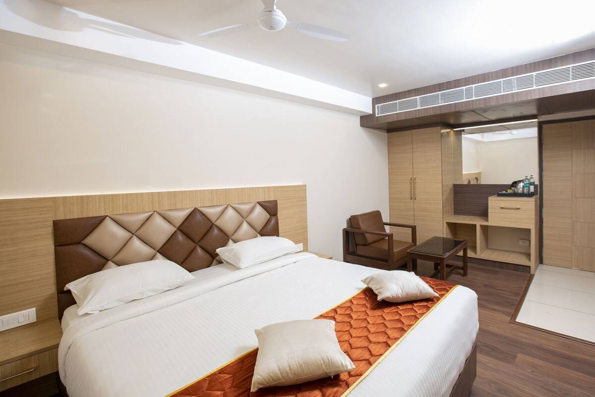 A hotel room with a bed, a chair, a desk, and a wardrobe.