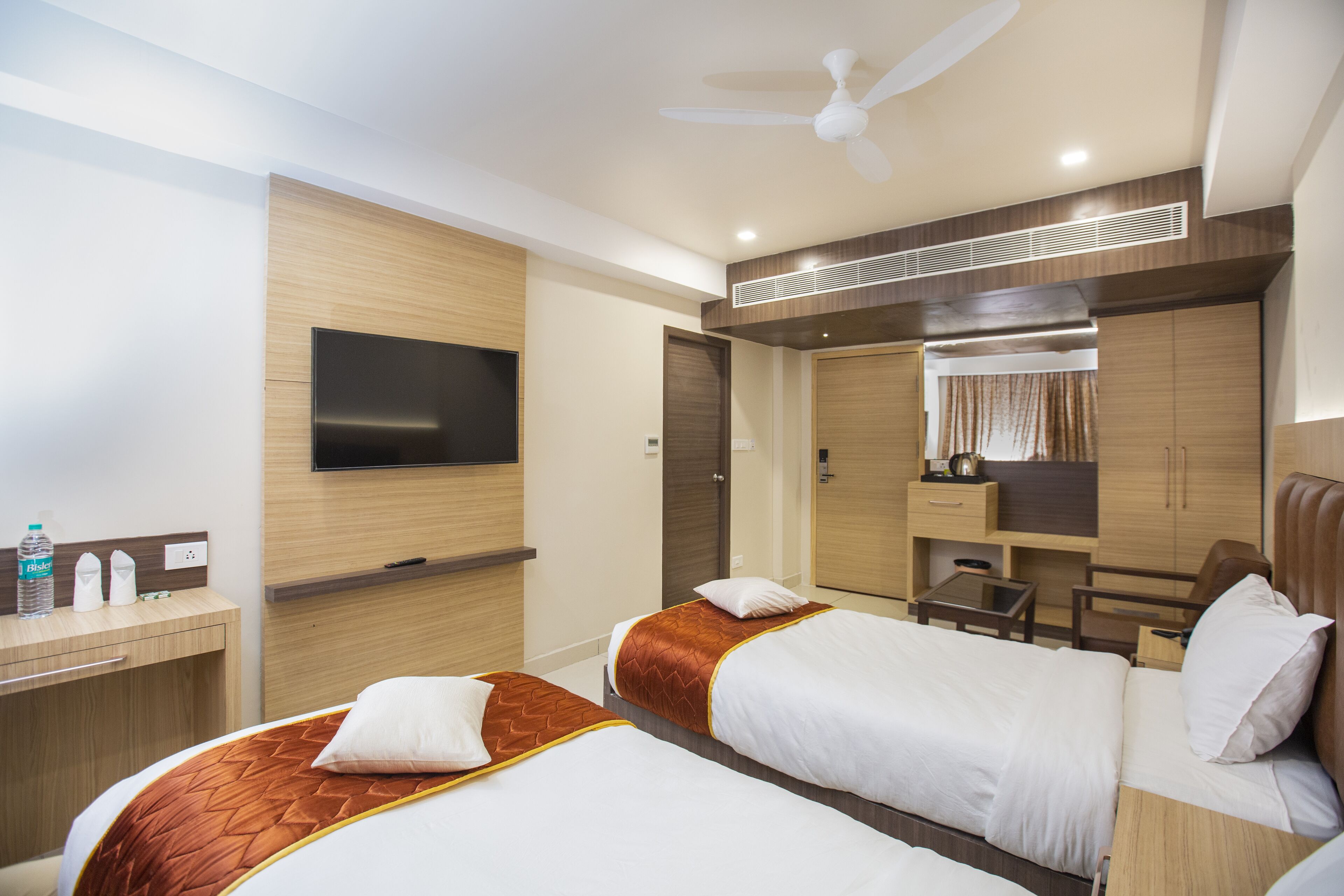 Una habitación de hotel con dos camas, televisión, escritorio y armario.