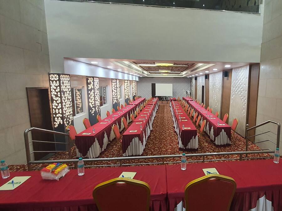 A conference room with long tables, chairs, and a projector screen at the front.