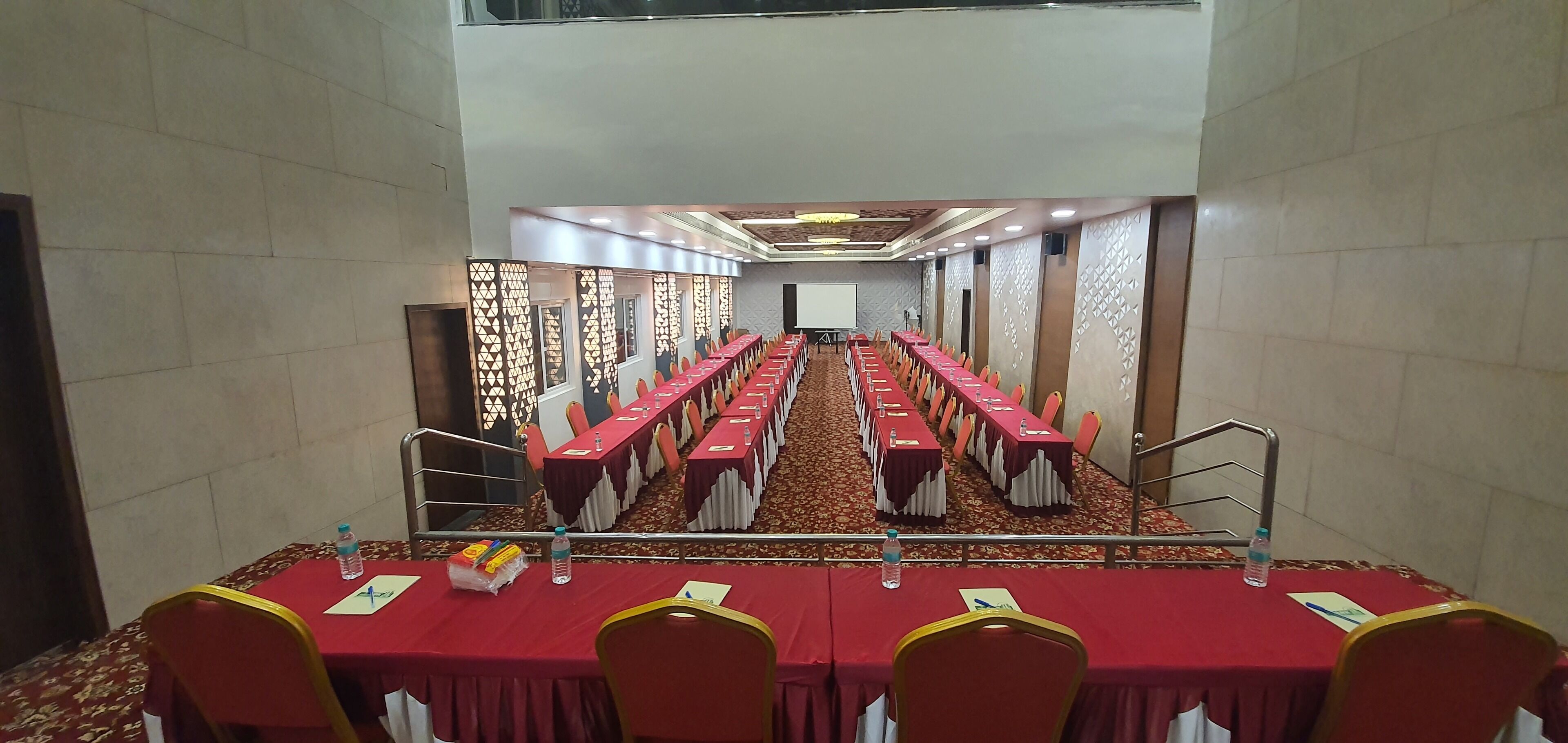 A conference room with long tables, chairs, and a projector screen.