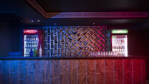 A bar area with a marble counter, shelves of liquor bottles, and a neon-lit wall. - Hotel Ark (Kumbakonam)