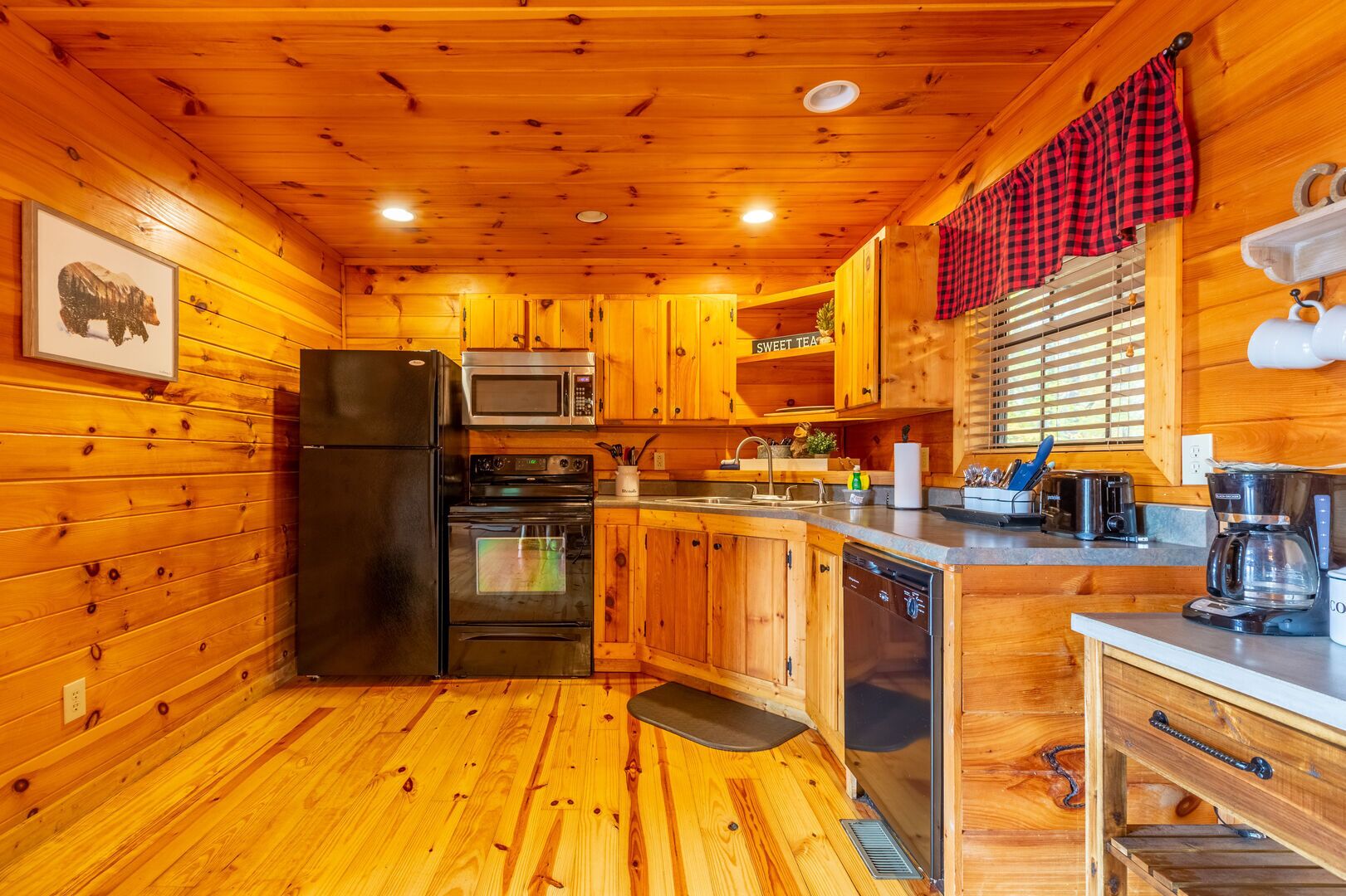 A compact kitchen with wooden cabinets, a refrigerator, a microwave, a dishwasher, and a coffee maker.