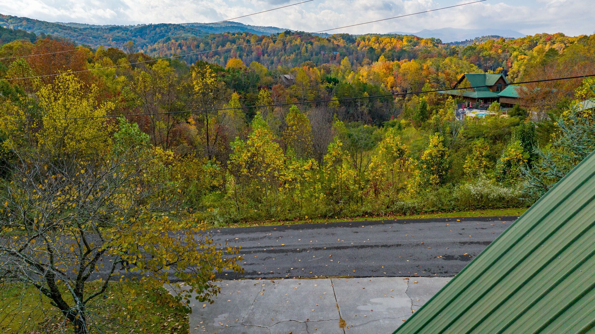 A view of a road with a building in the background surrounded by autumn foliage.