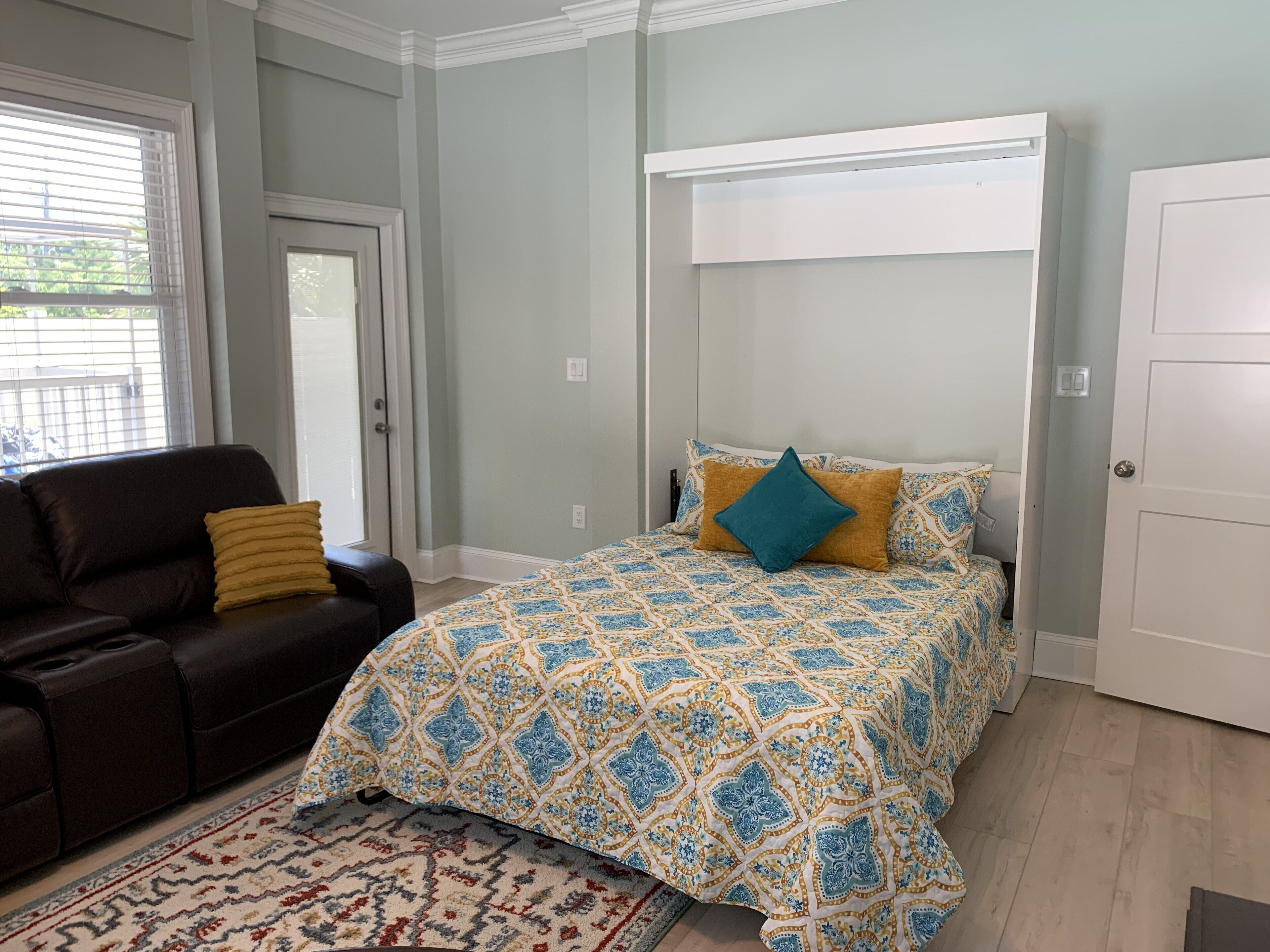 A bedroom with a bed, a couch, and a door.