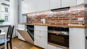 Una cocina moderna con armarios blancos, salpicadero de ladrillo y electrodomésticos de acero inoxidable.