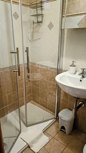 Ein Badezimmer mit Duschkabine aus Glas, einem weißen Waschbecken und einer Toilette.
