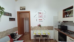 Eine kleine Küche mit Esstisch, Herd und Kühlschrank.