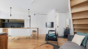 Een moderne woonruimte met een keuken, een bank, een televisie en een trap.