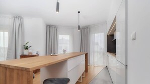 Een moderne keuken met een houten kookeiland, witte kastjes en een zwarte stoel.