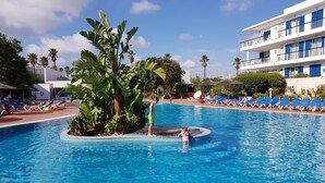 A pool with a central island surrounded by lounge chairs, palm trees, and a building with balconies. - Spacious Marina Apartment lovely balcony view, near to pool, WiFi & UK Tv (Lagos)