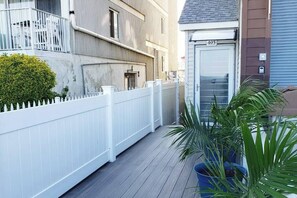 Een woongebouw met een witte picket fence, een deur met daarop '405' en potplanten.