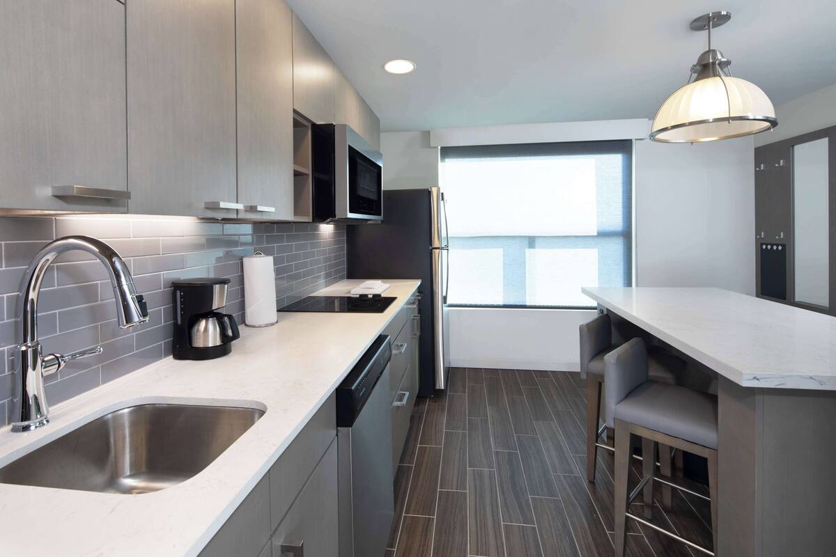 A modern kitchen with stainless steel appliances, a built-in oven, and a coffee maker.