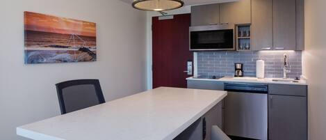 A modern kitchen with a white countertop, stainless steel appliances, and a pendant light.