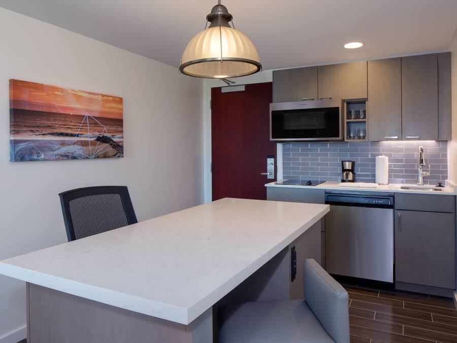 A modern kitchen with a white countertop, stainless steel appliances, and a pendant light.