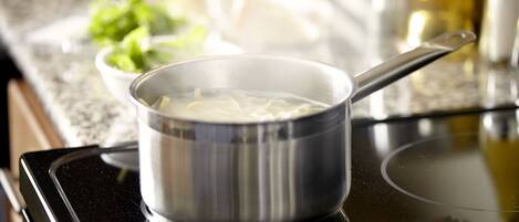 A stainless steel pot on a stove with noodles in it.