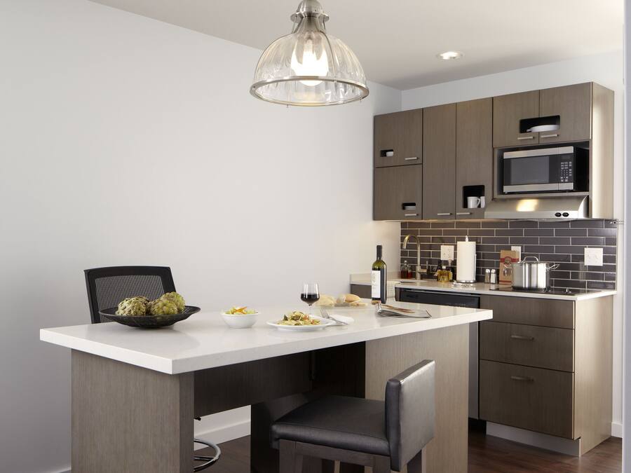 A modern kitchen with a central island, dark wood flooring, and stainless steel appliances.