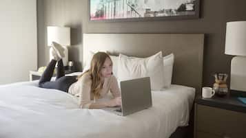 A hotel room with a bed, a laptop, a coffee maker, and a framed picture on the wall.