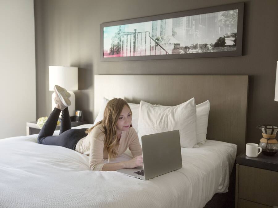 Une chambre d’hôtel avec un lit, un ordinateur portable, une machine à café et un tableau encadré au mur.