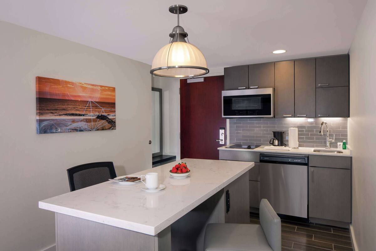 A modern kitchen with a central island, stainless steel appliances, and a pendant light.
