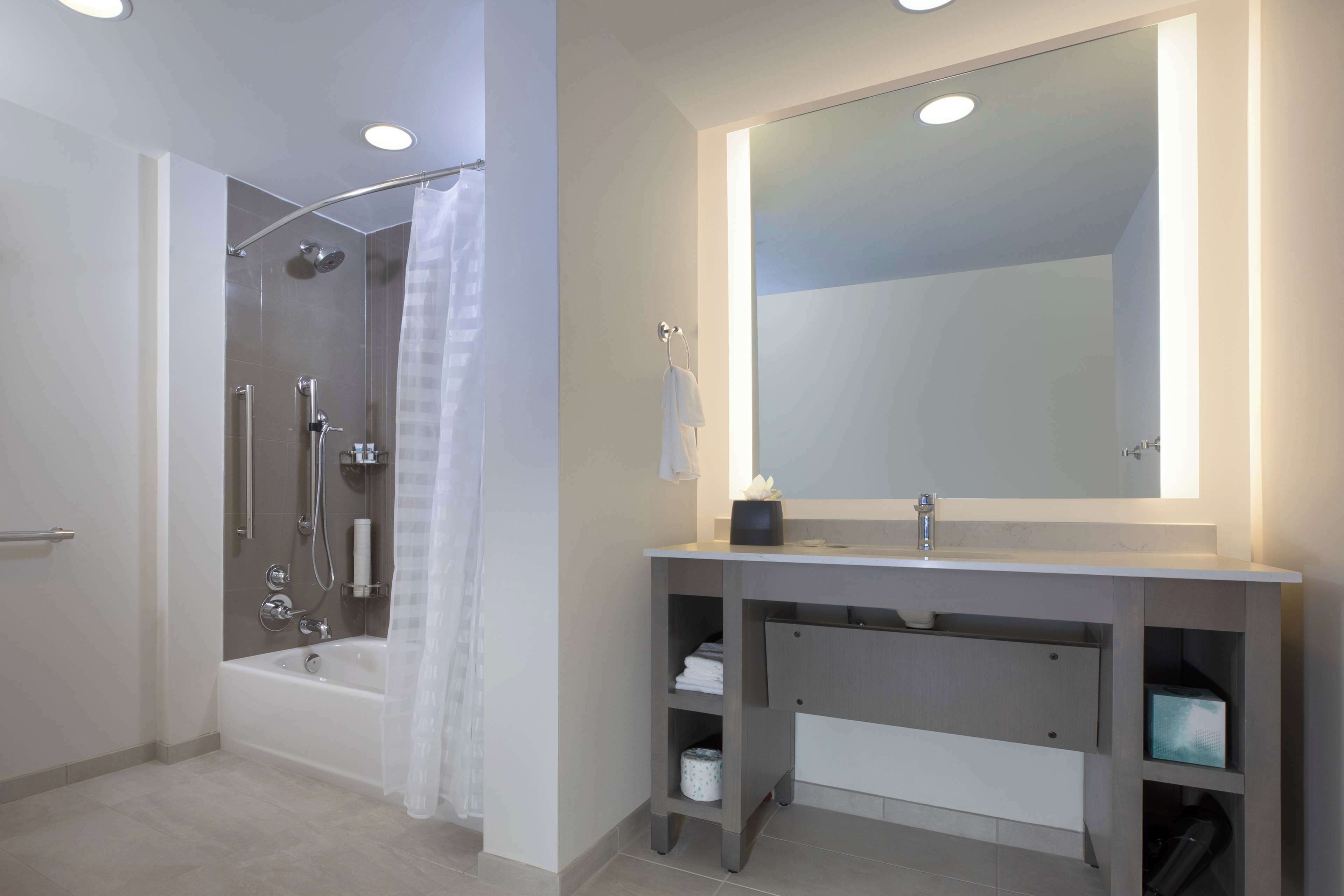 Un baño moderno con bañera, ducha, tocador y un espejo grande.