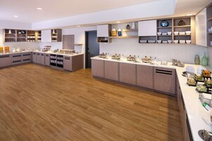 Una cocina moderna con armarios de madera, encimeras blancas y estantes empotrados.