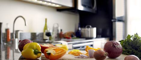 A kitchen counter with various vegetables, a cutting board, and a knife.