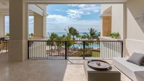 A balcony with a view of a pool and palm trees, a sofa, and a table with a decorative item. - Breathless 4You, Oceanfront Penthouse (Cap Cana)