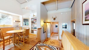 Een ruime keuken met houten meubels, een eethoek en een gang naar een slaapkamer.