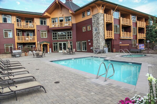 A hotel with a pool area, outdoor seating, and a stone facade.