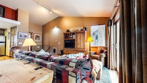 Um quarto aconchegante com uma cama, um armário de madeira, uma televisão e uma janela com persianas.