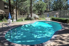Relax by the pool surrounded by a deck and lush greenery.