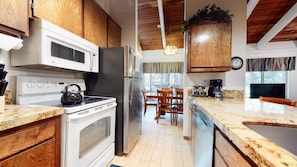 Enjoy cooking in this well-equipped kitchen with a microwave, refrigerator, and kettle, and dine at the wooden table with chairs.