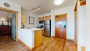 A modern kitchen with wooden cabinets, a stainless steel refrigerator, and a built-in microwave. - Sunstone 109 Remodeled Condo Great Complex Amenities with Ski-In Ski-Out by RedAwning (Mammoth Lakes)