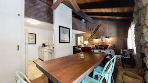 Une cuisine rustique avec une table en bois, des armoires blanches et un mur en pierre.