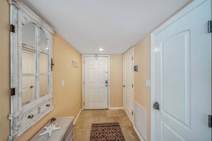 A hallway with a white door, a white-framed mirror, and a starfish decoration on a dresser.