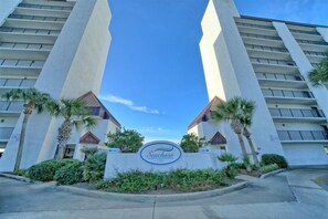 A Seachase hotel entrance with a clear sky, palm trees, and a sign.