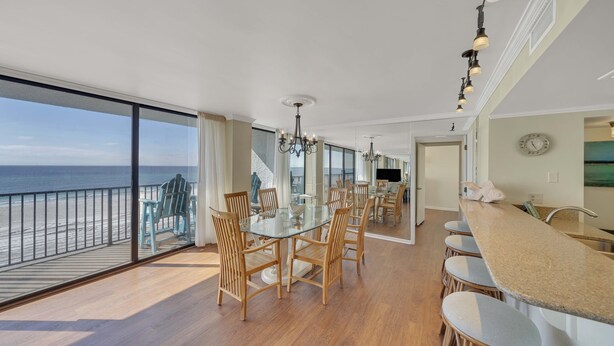 A spacious dining area with a glass table and chairs, overlooking a balcony with a view of the ocean. - FREE Perks! Updated Seachase Beachfront E304 Amazing Views from 3rd Floor! (Panama City Beach)