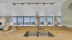 A kitchen with a granite countertop, stainless steel sink, and a chandelier. - FREE Perks! Updated Seachase Beachfront E304 Amazing Views from 3rd Floor! (Panama City Beach)