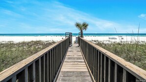A wooden boardwalk leading to a beach with a palm tree in the center. - FREE Perks! Updated Seachase Beachfront E304 Amazing Views from 3rd Floor! (Panama City Beach)