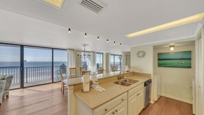 A kitchen with a large island, a view of the ocean, and a dining area with chairs. - FREE Perks! Updated Seachase Beachfront E304 Amazing Views from 3rd Floor! (Panama City Beach)
