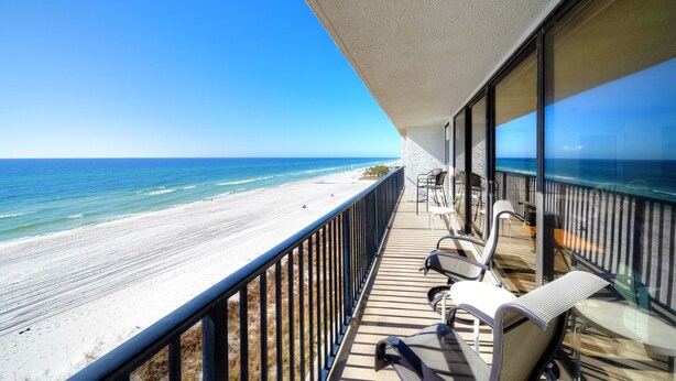 A balcony with a view of the beach and ocean.