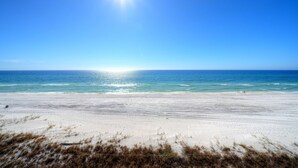A beach with a clear sky and the sun shining.