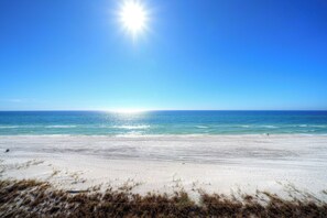 A beach with a clear sky and the sun shining.